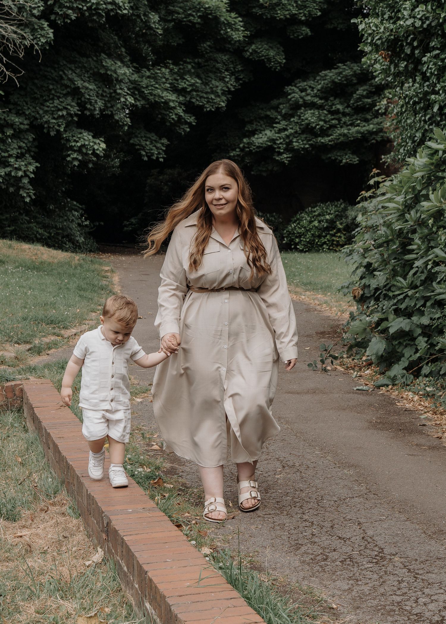 Family Photoshoot - People walk along a brick-edged pathway through a garden setting.