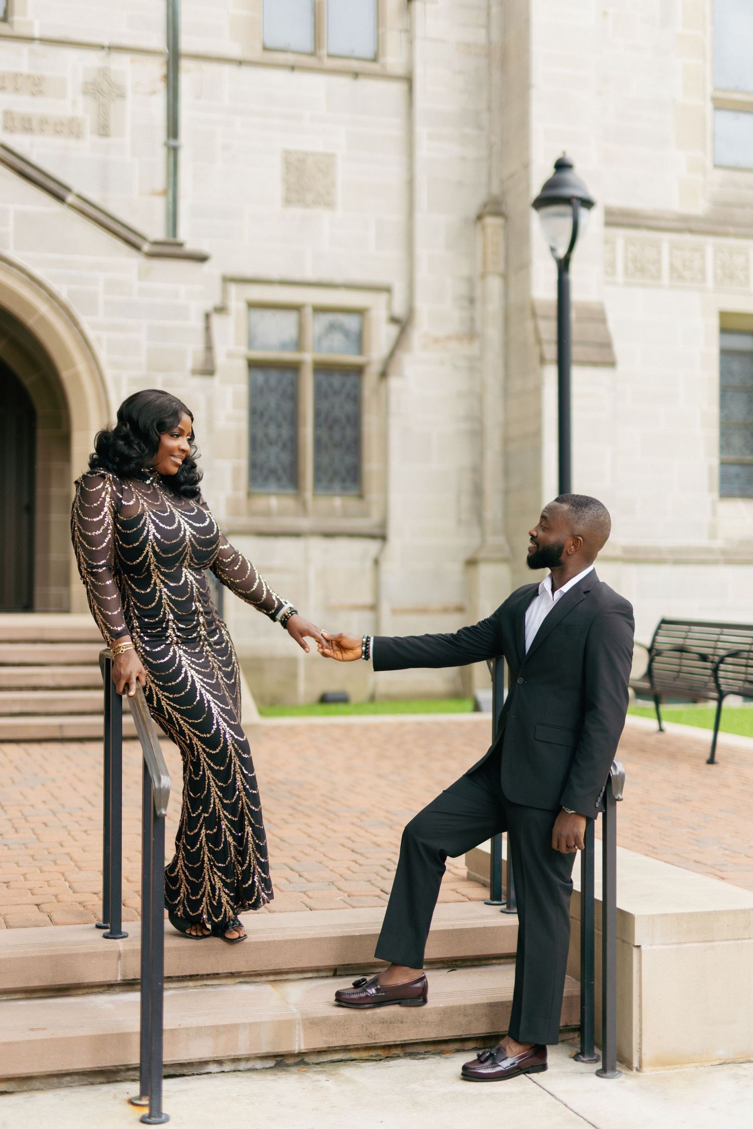 Romantic couple photo with red dress and grey suit against architectural column.