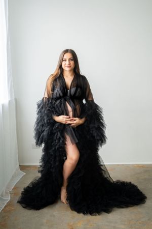 Flowing black tulle dress photographed against stark white studio walls.