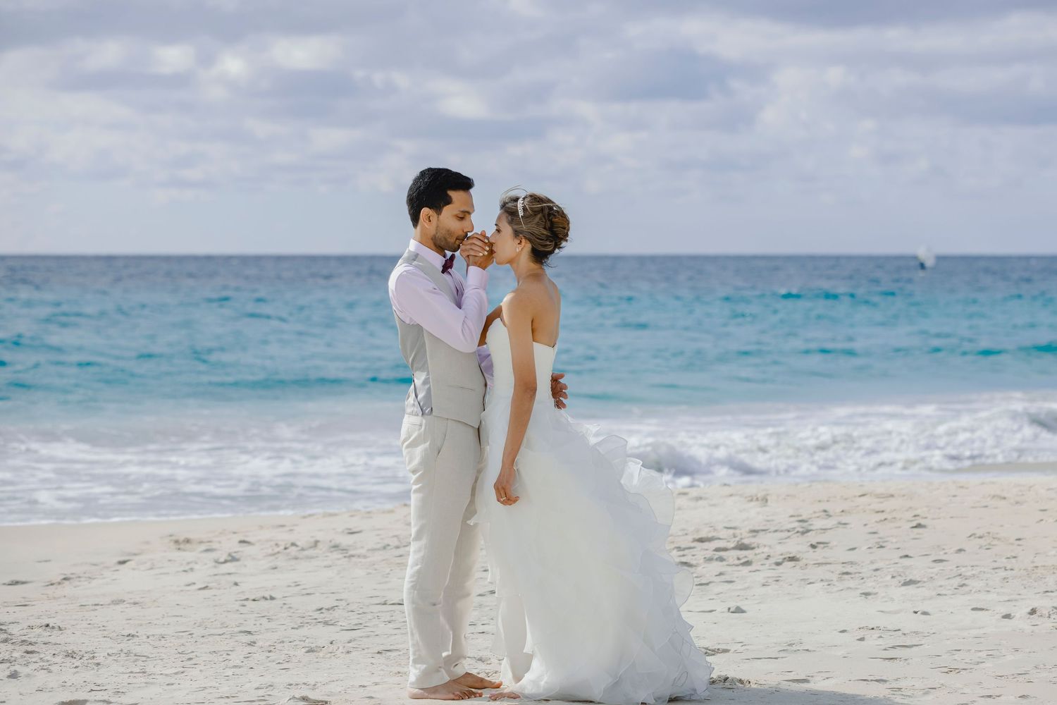 Couple standing on sand dune with flowing red dress against turquoise sky.