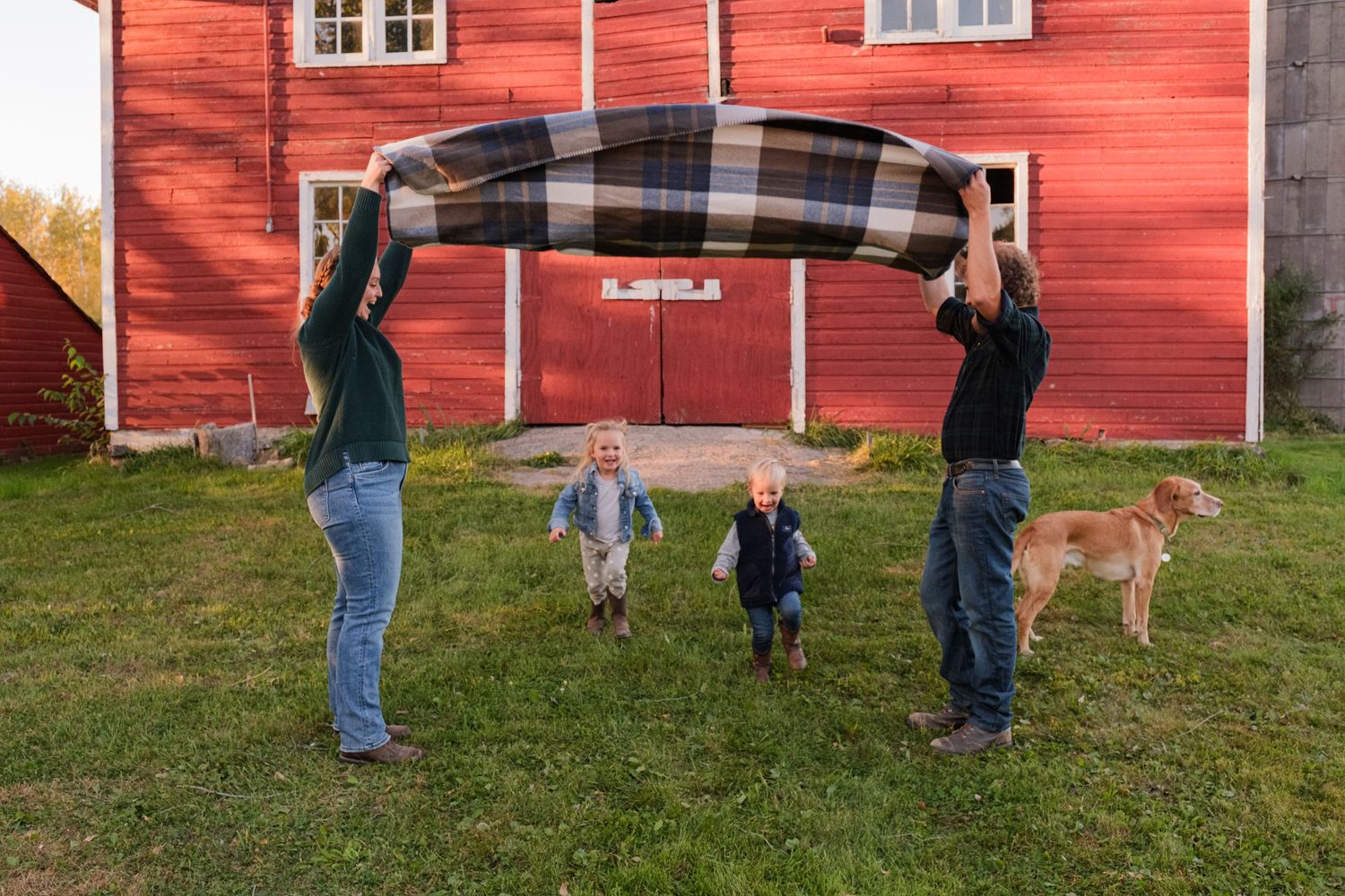 Family session at their family farm in front of a red barn