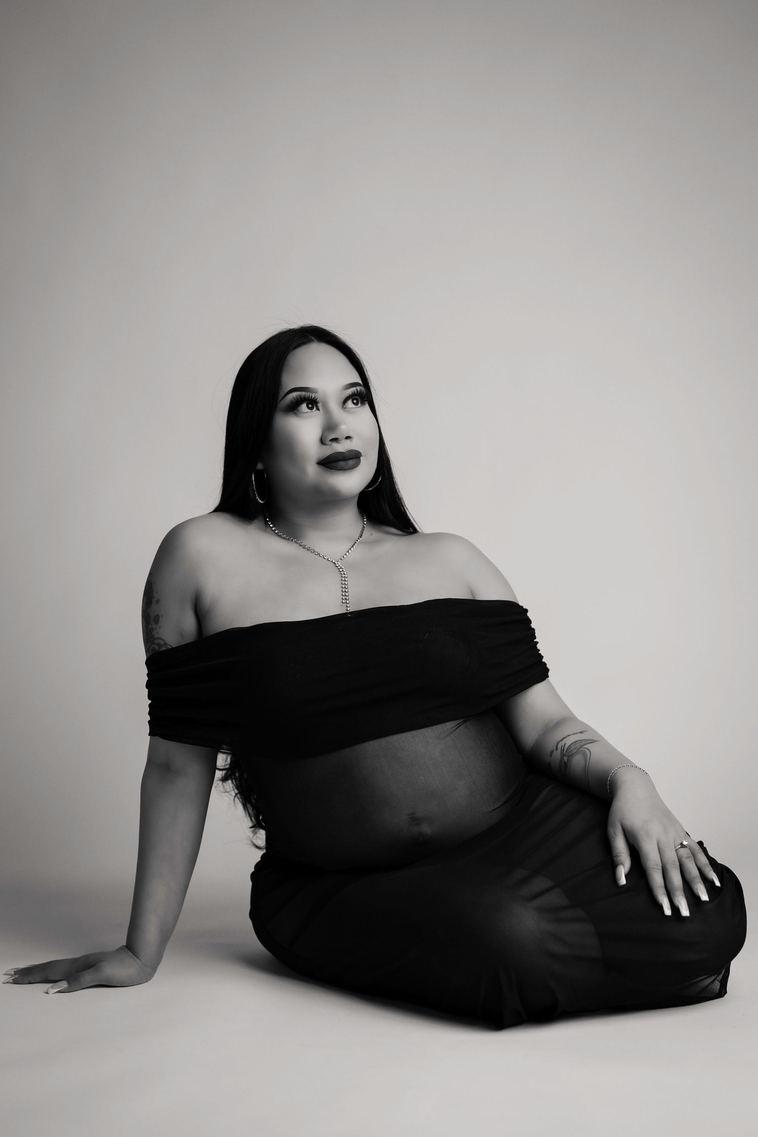 Artistic black and white maternity portraits feature elegant poses in an off-shoulder black dress.