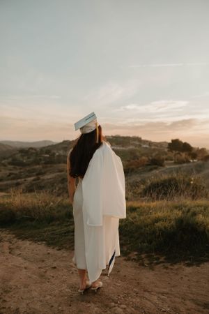 Silhouette of graduate in cap and gown against golden sunset hills for graduation and senior photos in Orange County