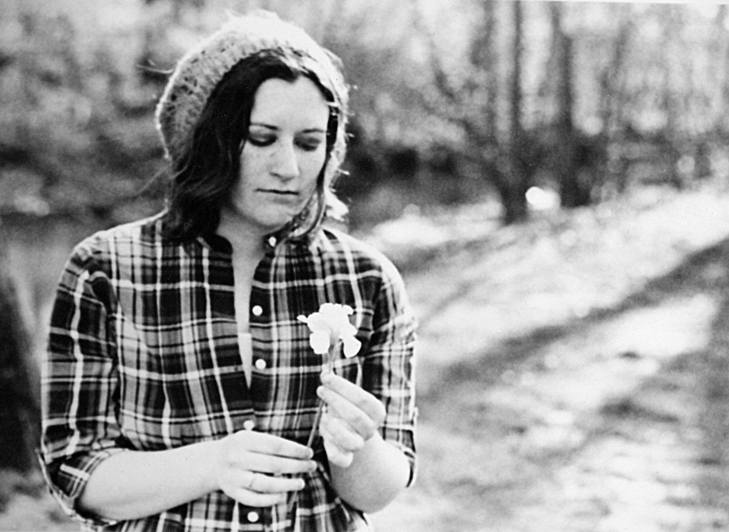 young woman stares wistfully at flower