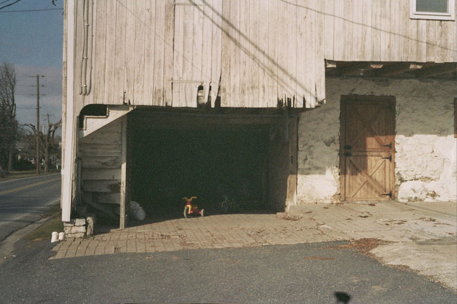 old barn, child's toy bike in shadow