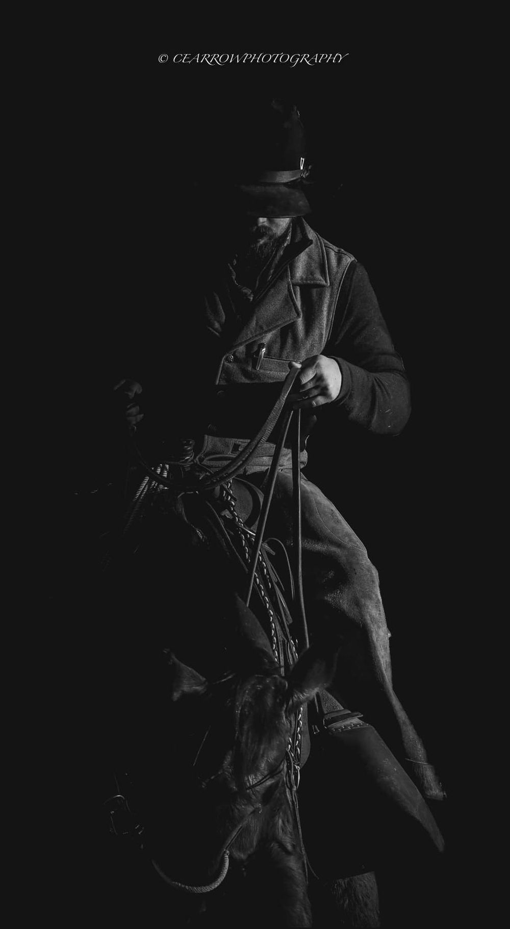Dramatic black and white photo of a cowboy with rope and western gear at night.
