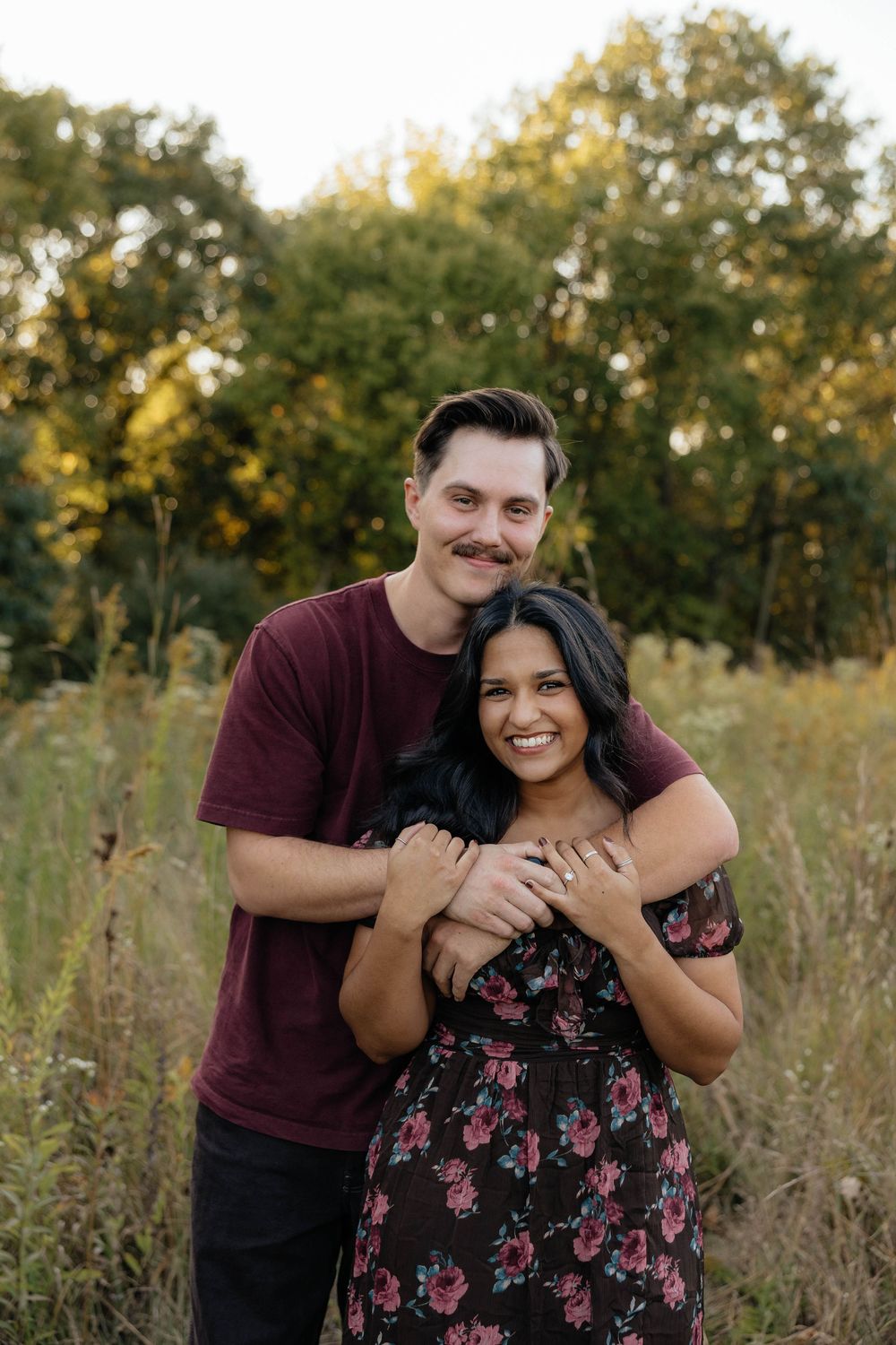 A couple embraces in a golden field during sunset as they pose for romantic outdoor portraits.