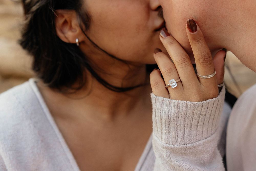 Close-up view of someone wearing a cozy cream sweater while touching their face with burgundy manicured nails.