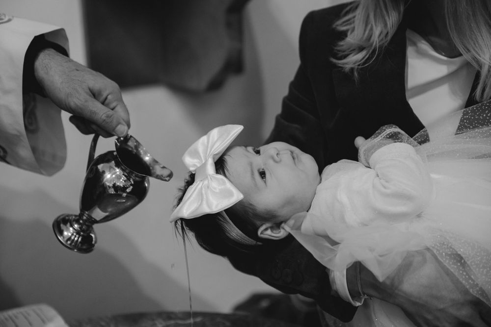 Black and white photo of a baptism ritual with holy water being poured.