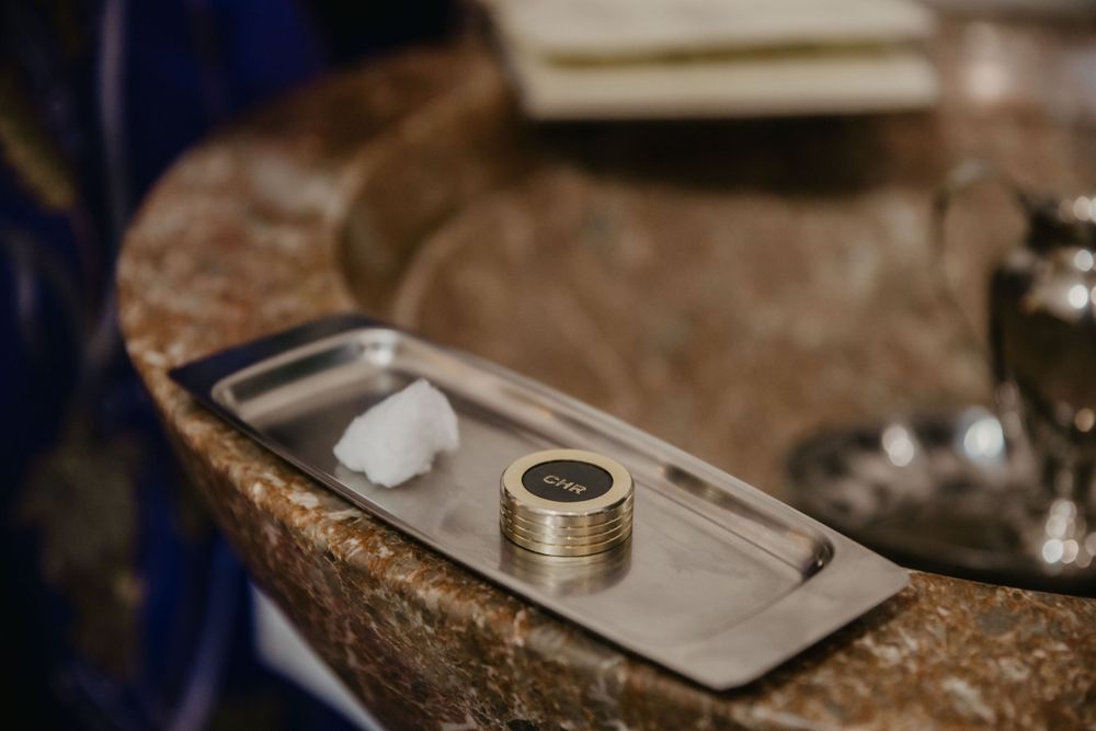 Silver baptismal items and rings displayed on a metal tray.