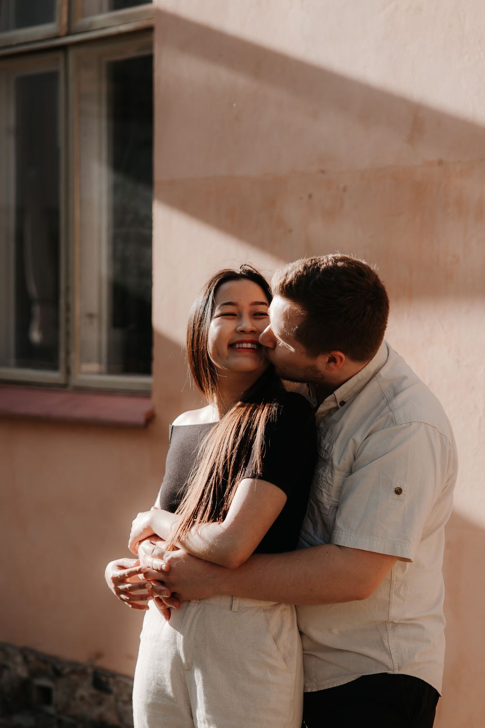 Joyful couple embracing outdoors during sunset maternity session.