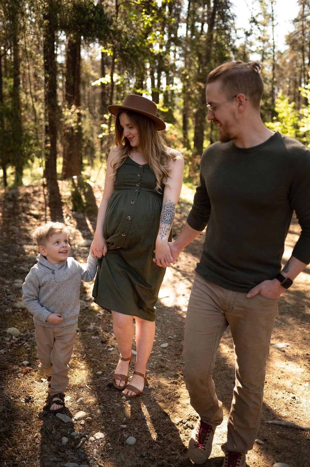 Family walking together on a sunlit forest trail in casual attire.