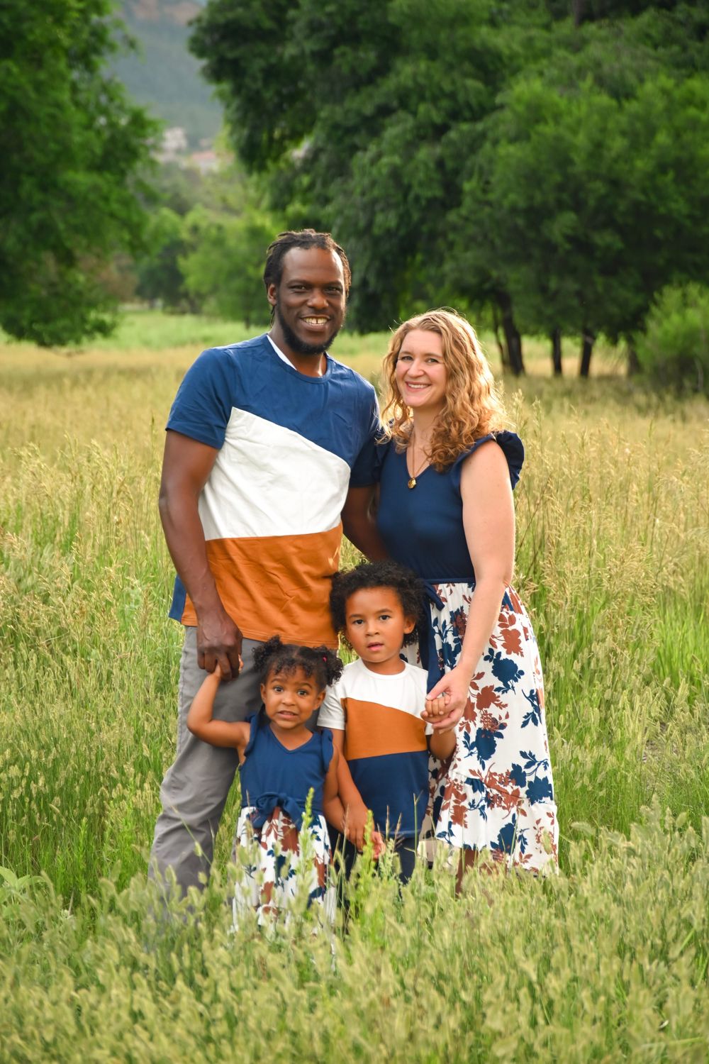 Family enjoying a sunny afternoon together in a meadow of tall grass.