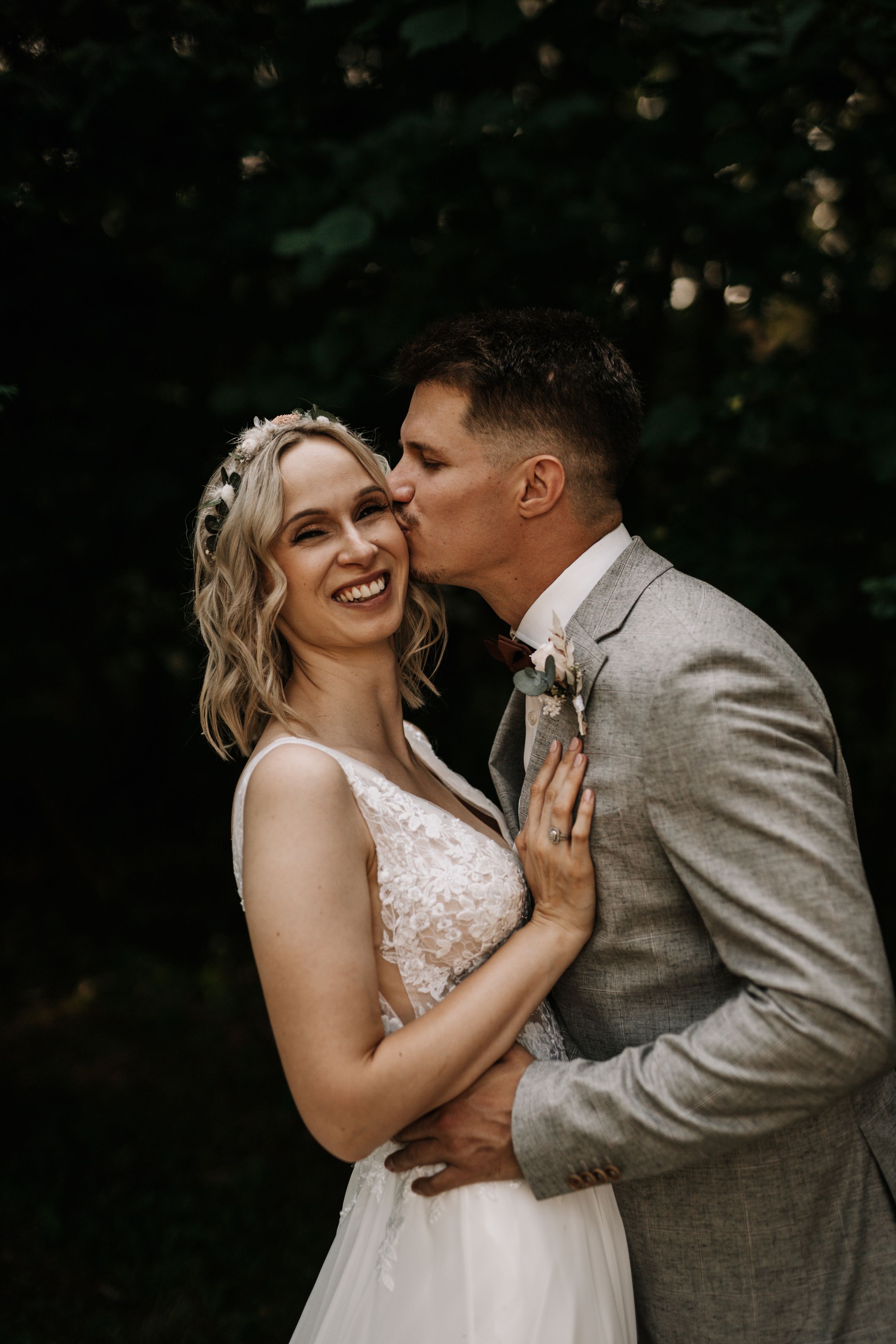 An intimate moment between newlyweds sharing laughter and joy in a garden setting.