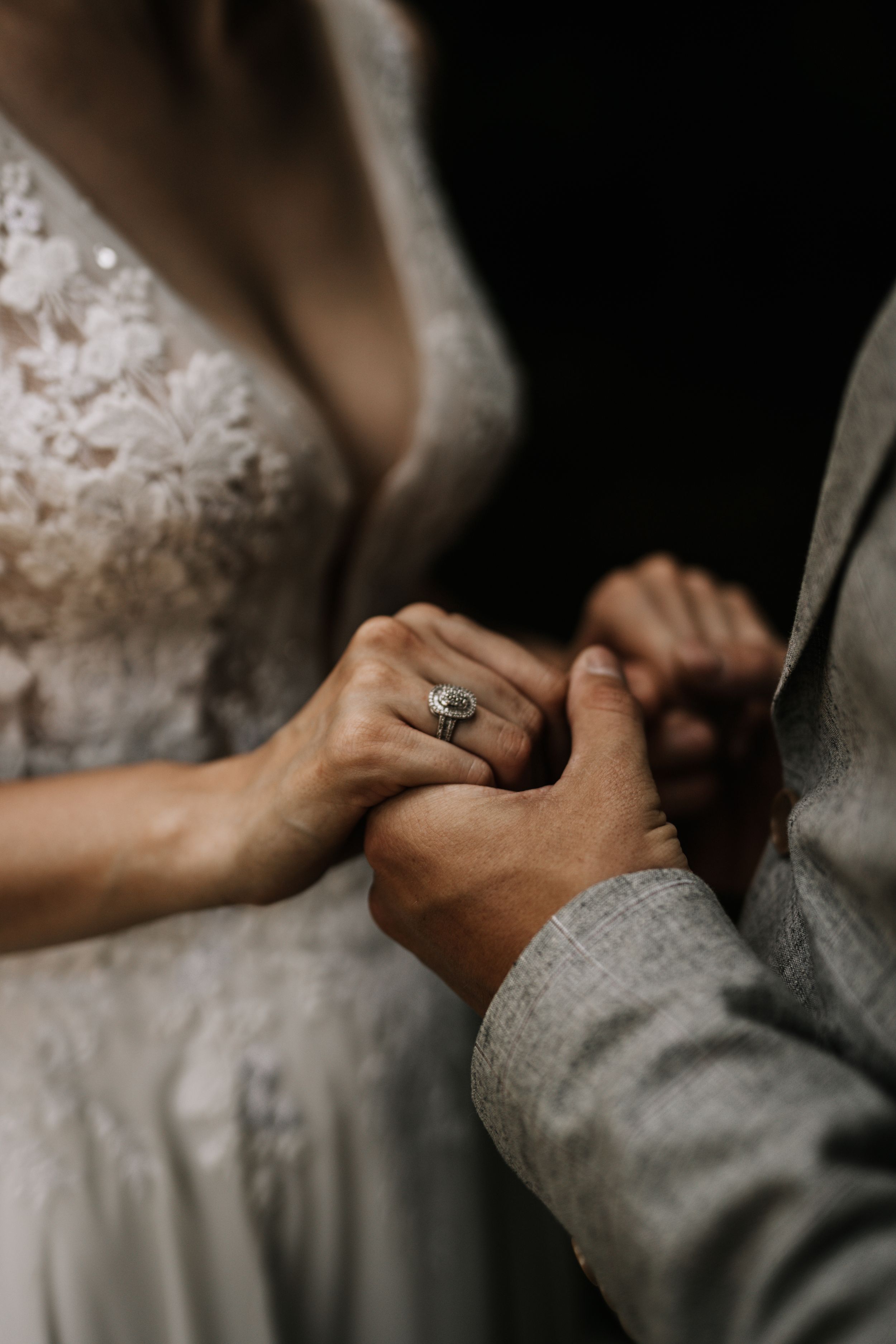 Close-up of hands and wedding ring during an intimate moment between newlyweds.