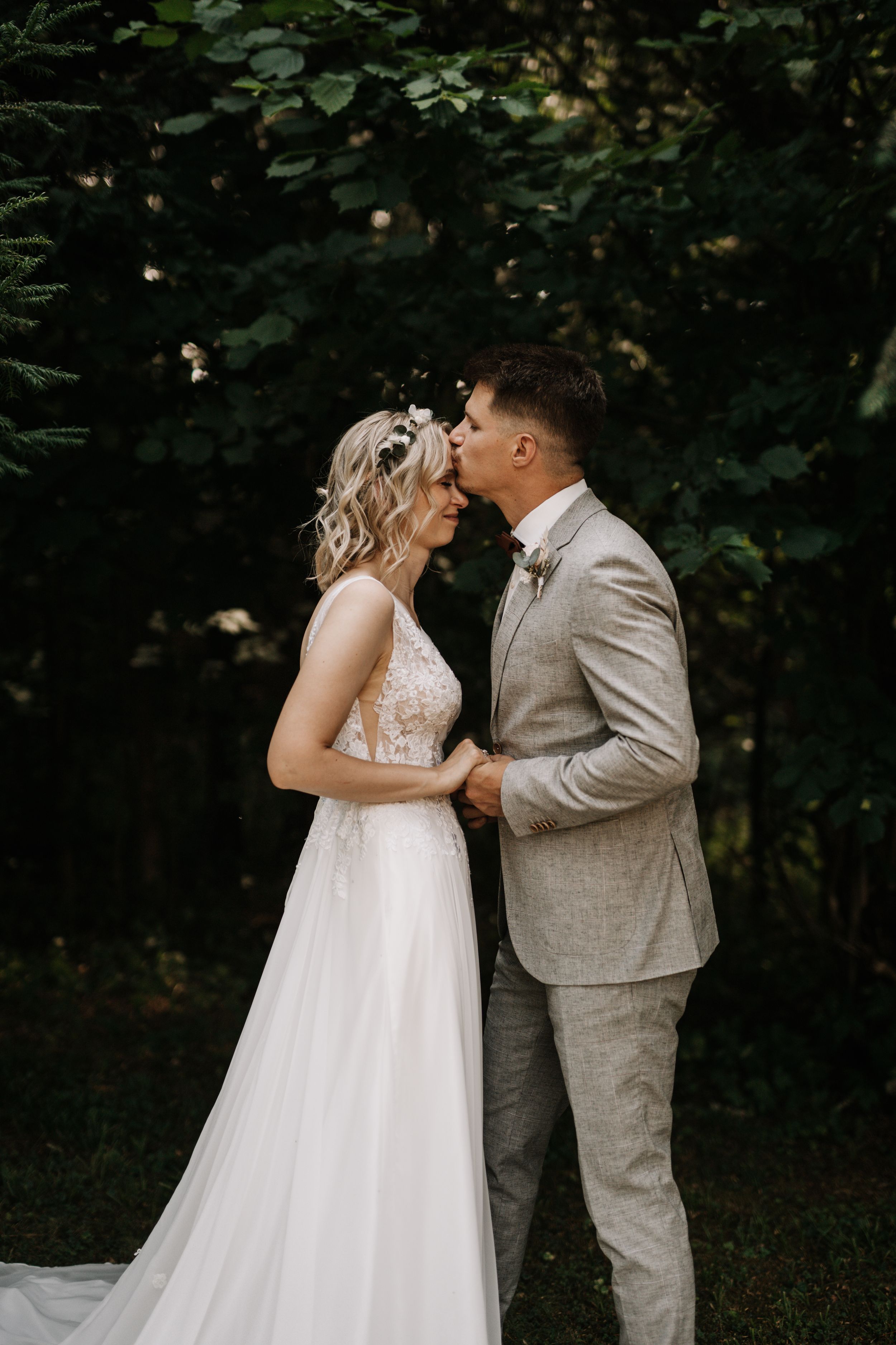 A tender moment between newlyweds against a dark forest backdrop.