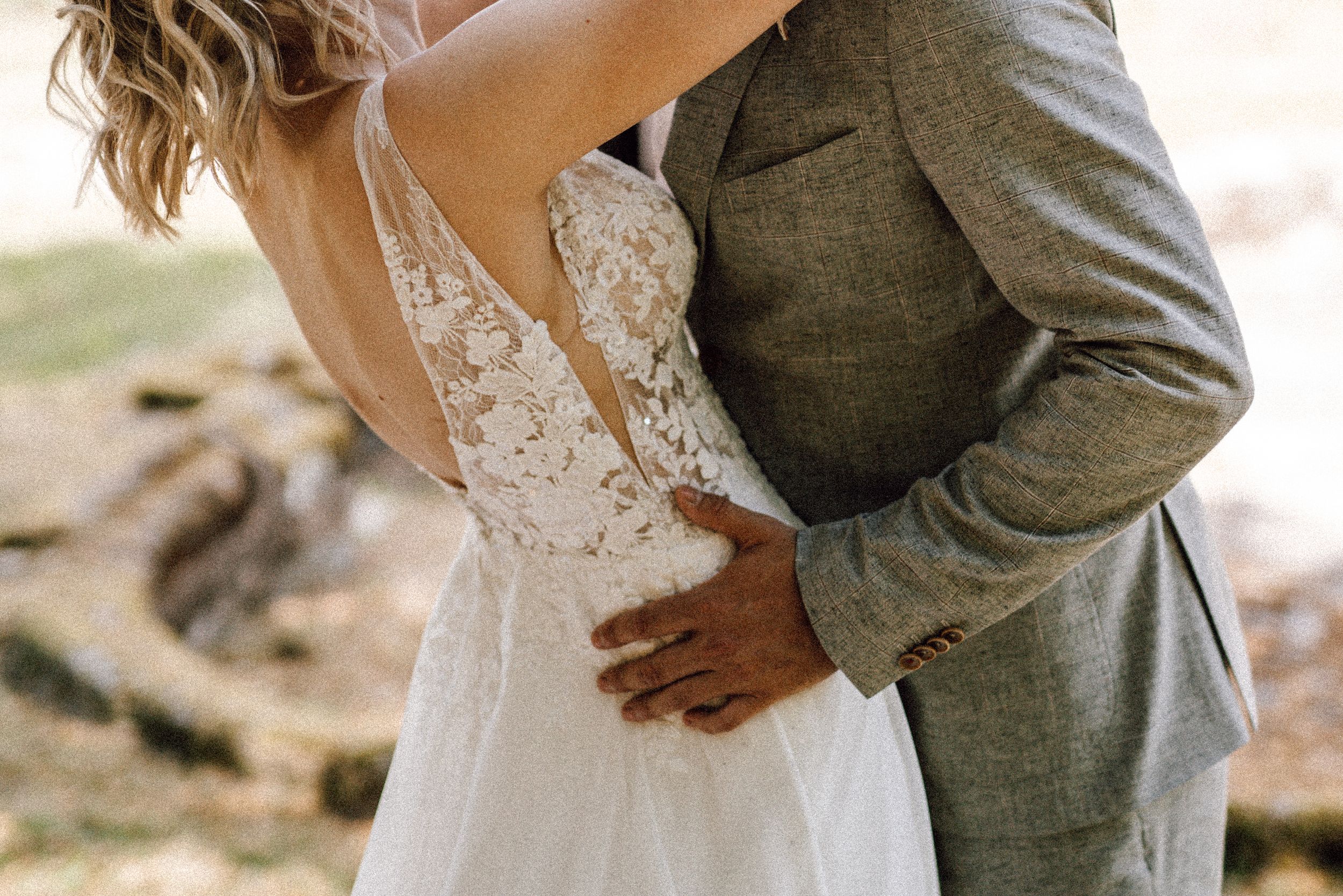 Close-up shot of couple embracing in romantic outdoor wedding setting.