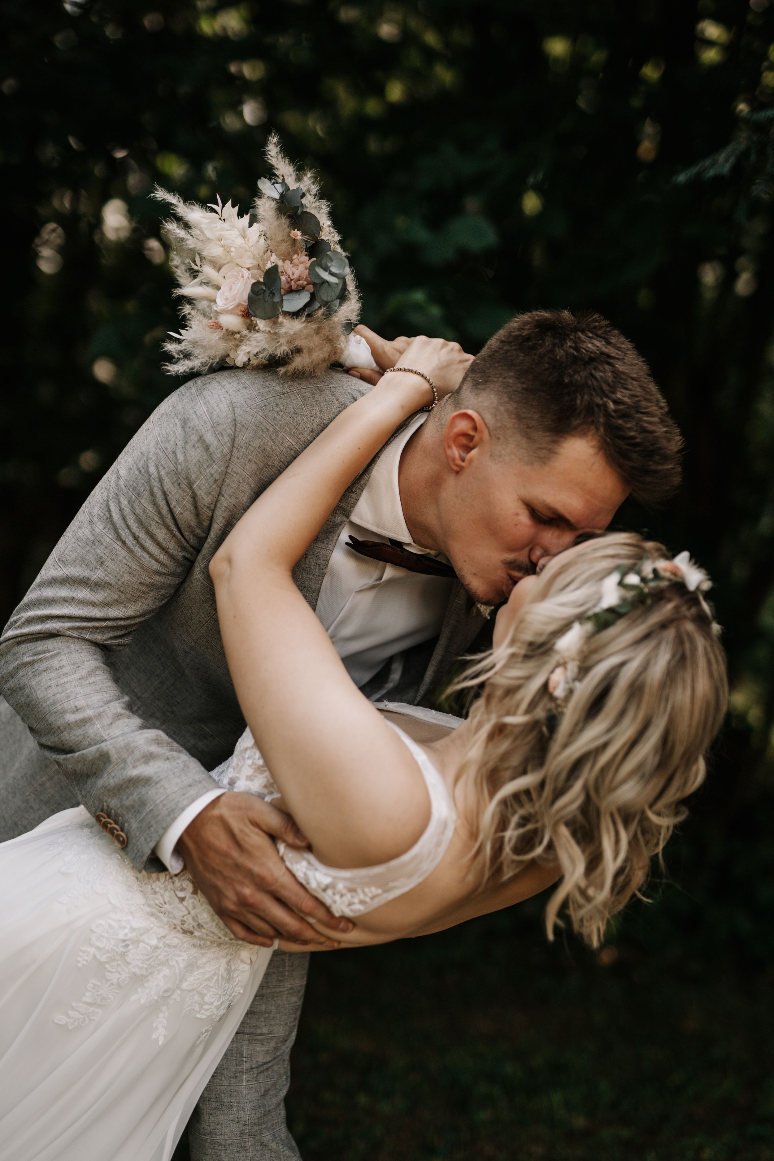 Intimate wedding photo capturing a romantic dip pose between newlyweds in an outdoor garden setting.