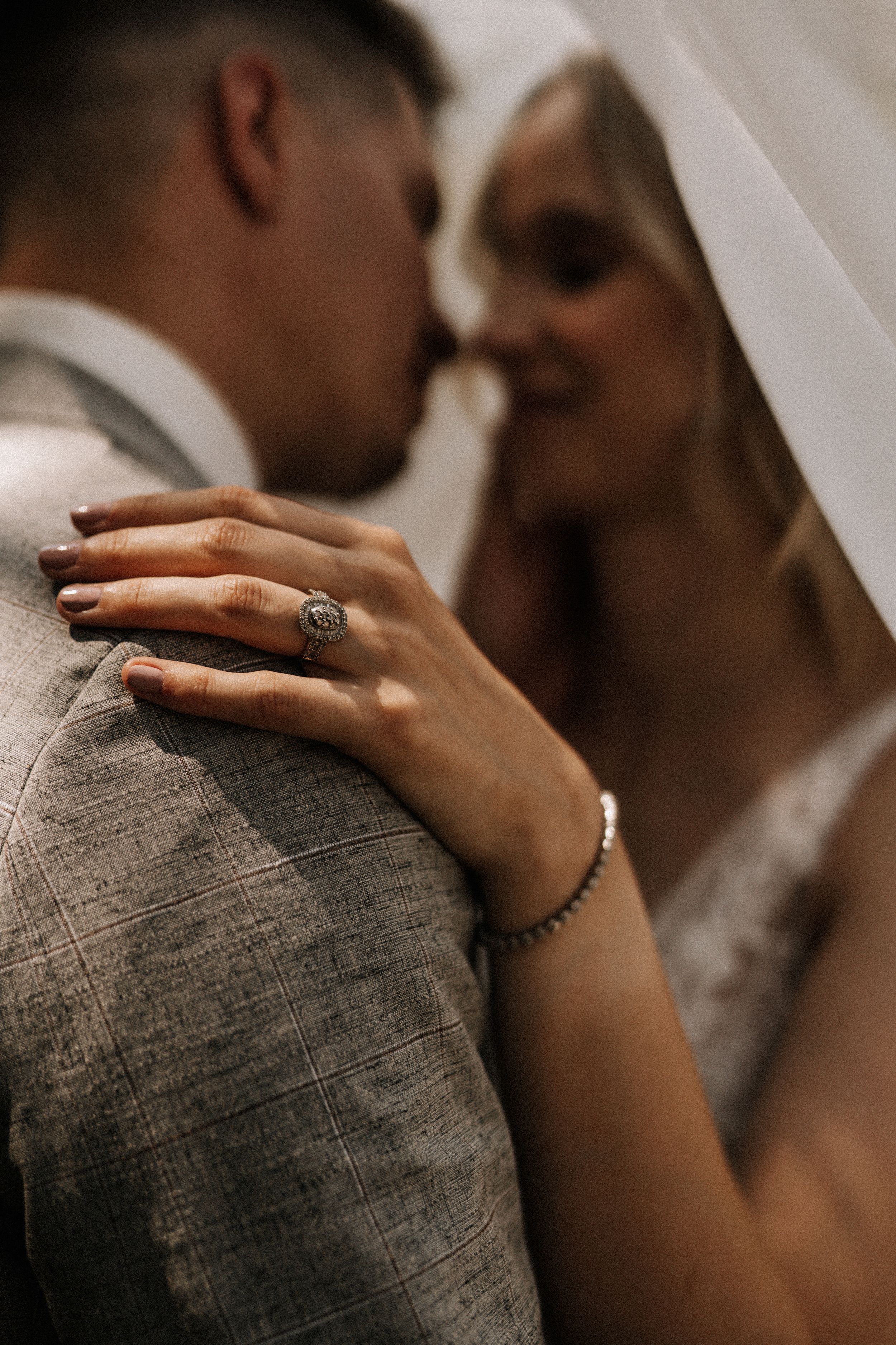 Close-up detail shot of engagement ring as couple shares intimate moment.