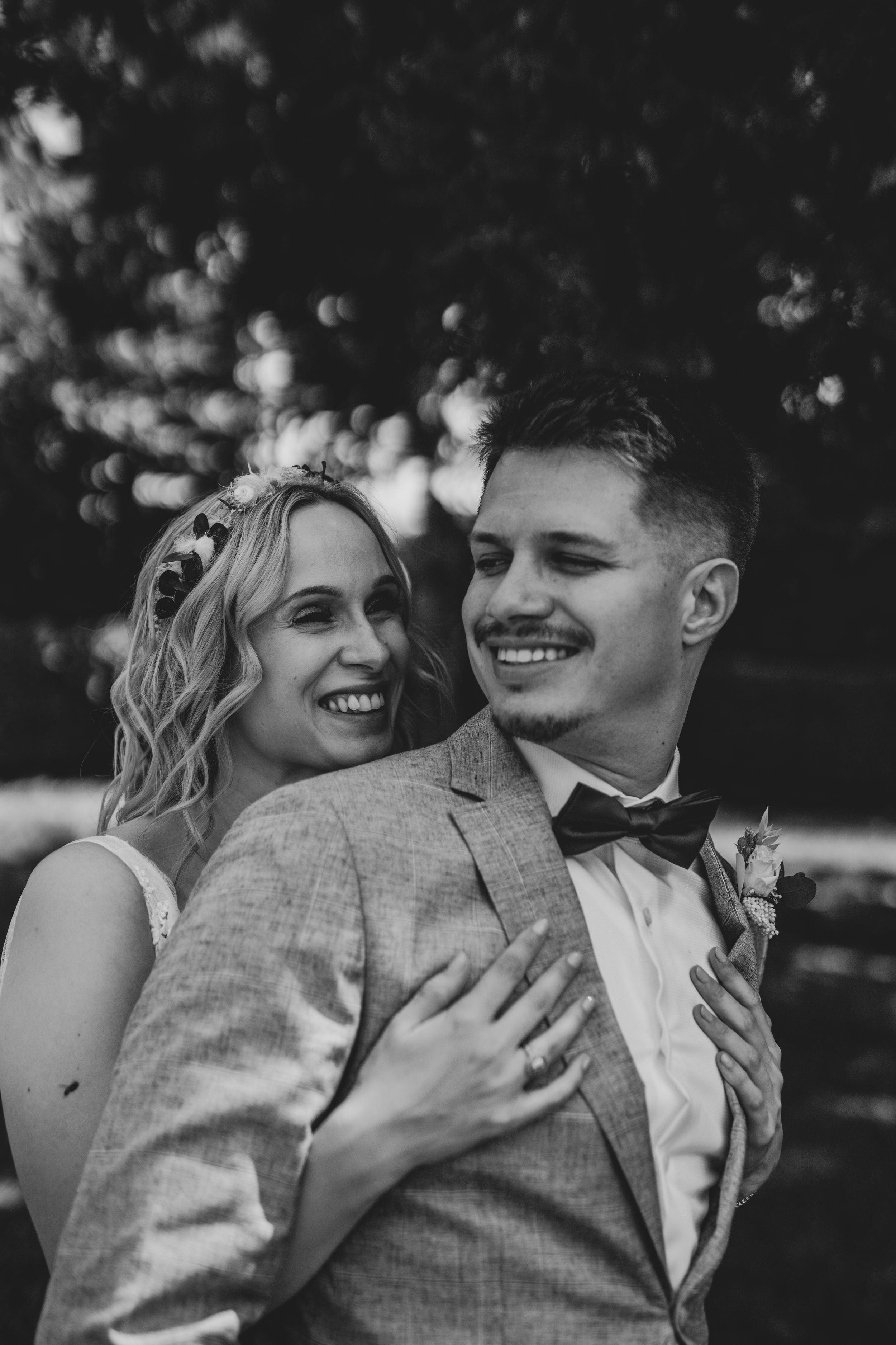 Black and white wedding portrait capturing joyful laughter between newlyweds.