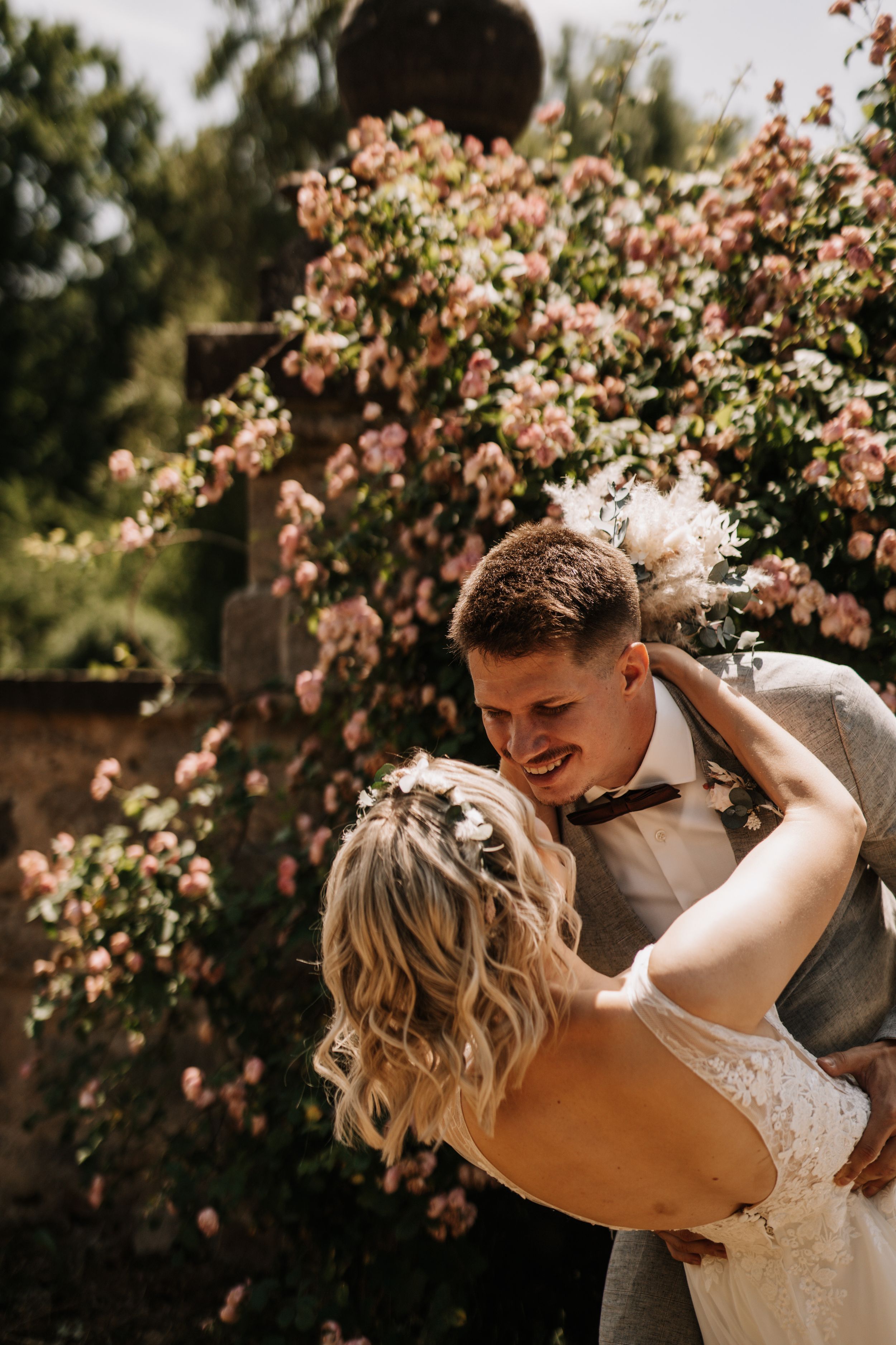 Couple sharing intimate moment by blooming pink roses in garden.