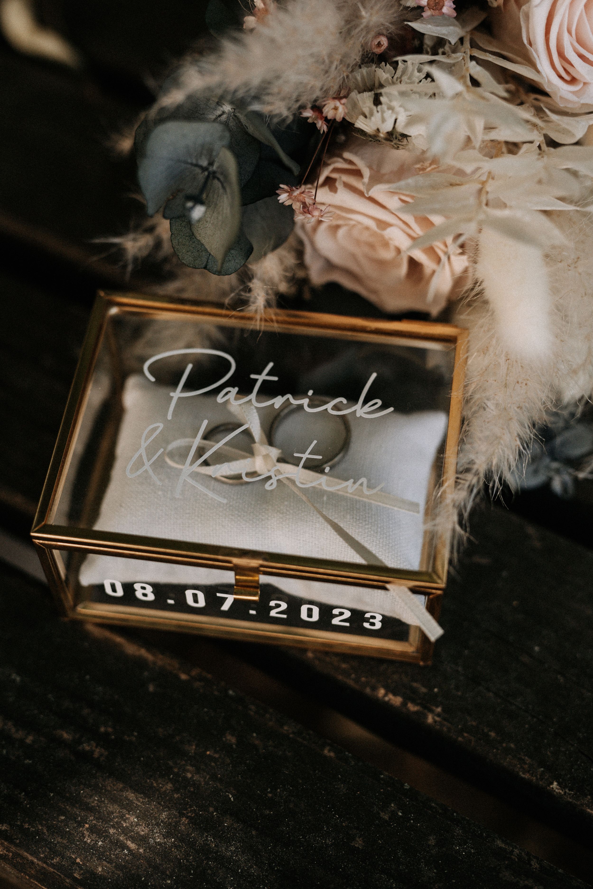 Wedding date display with names in elegant gold frame with feather decorations.