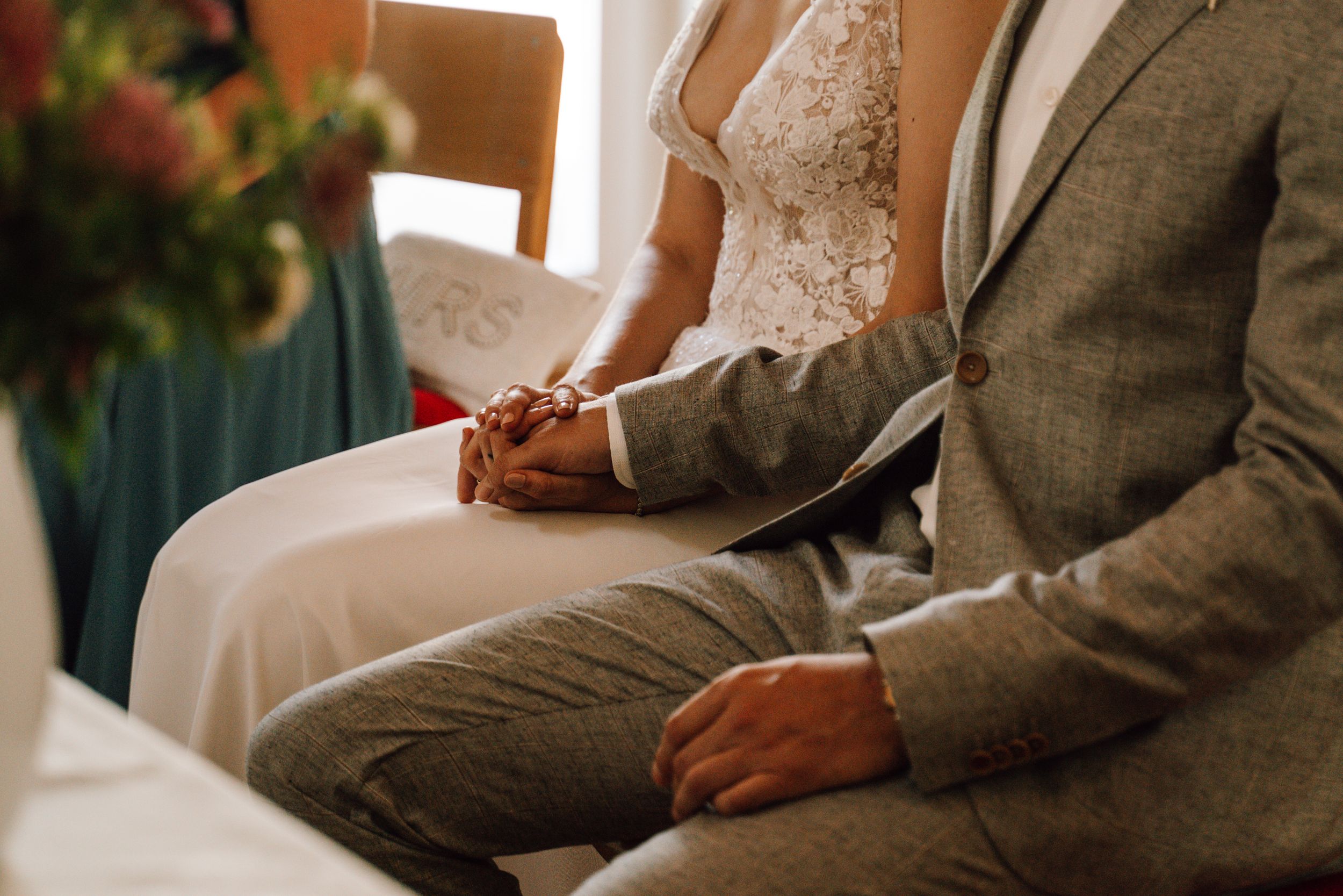 Couple holding hands during wedding ceremony in elegant attire.