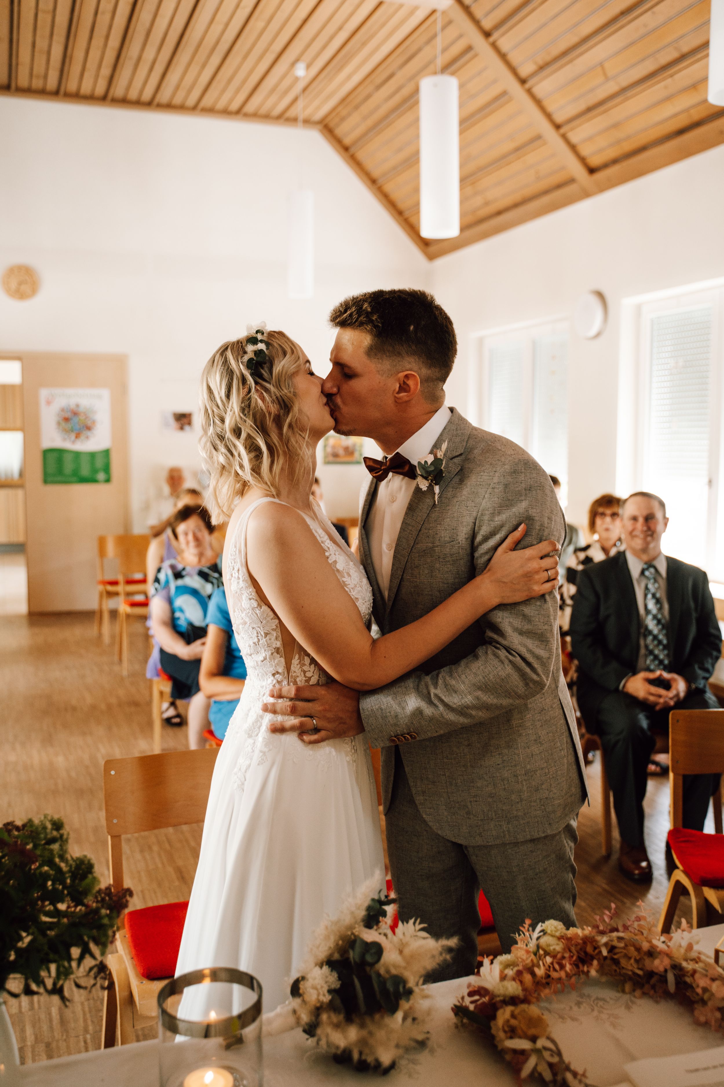 Wedding ceremony in bright indoor venue with wooden ceiling and natural lighting.