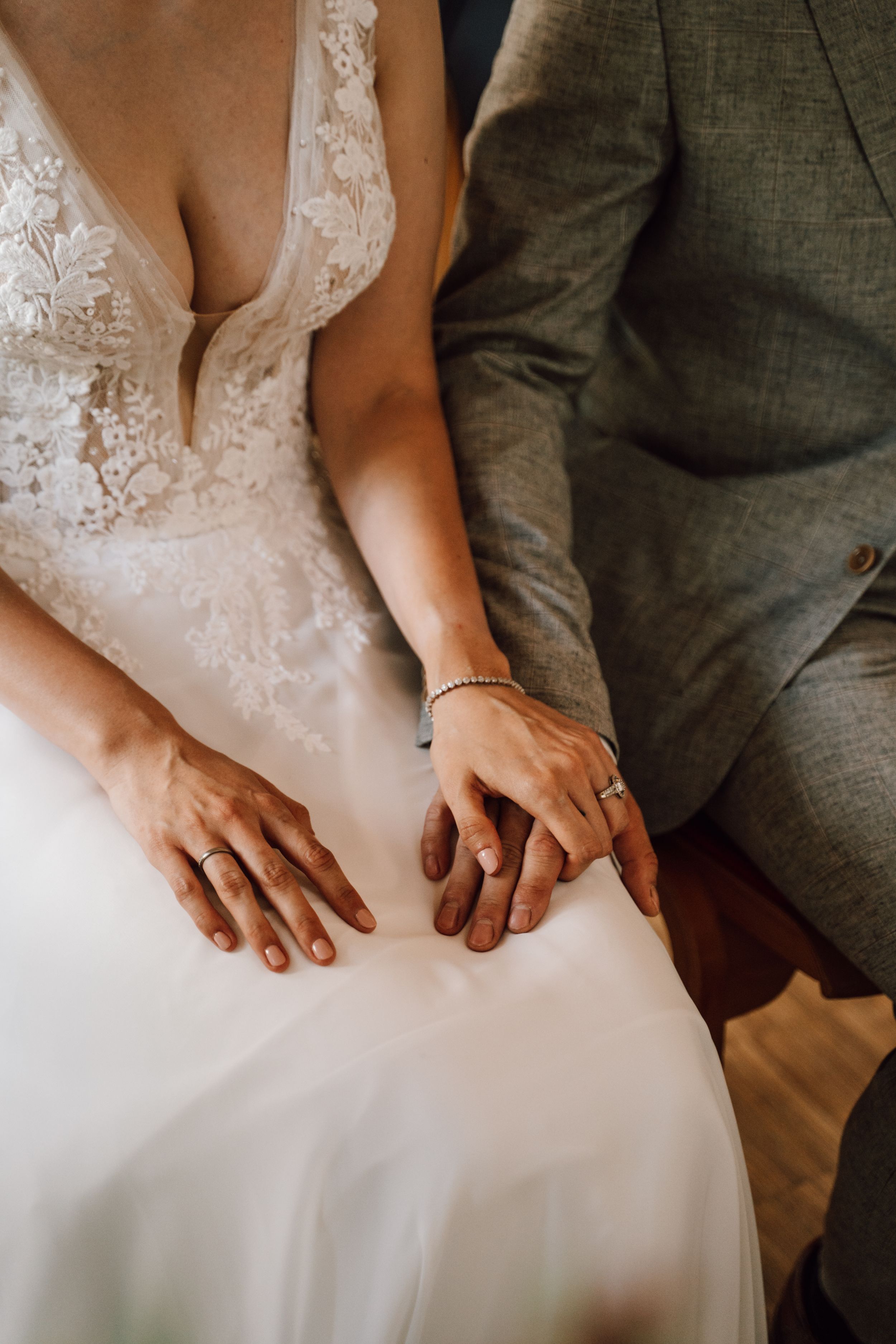 Close-up of couple's hands resting together after wedding ring exchange.