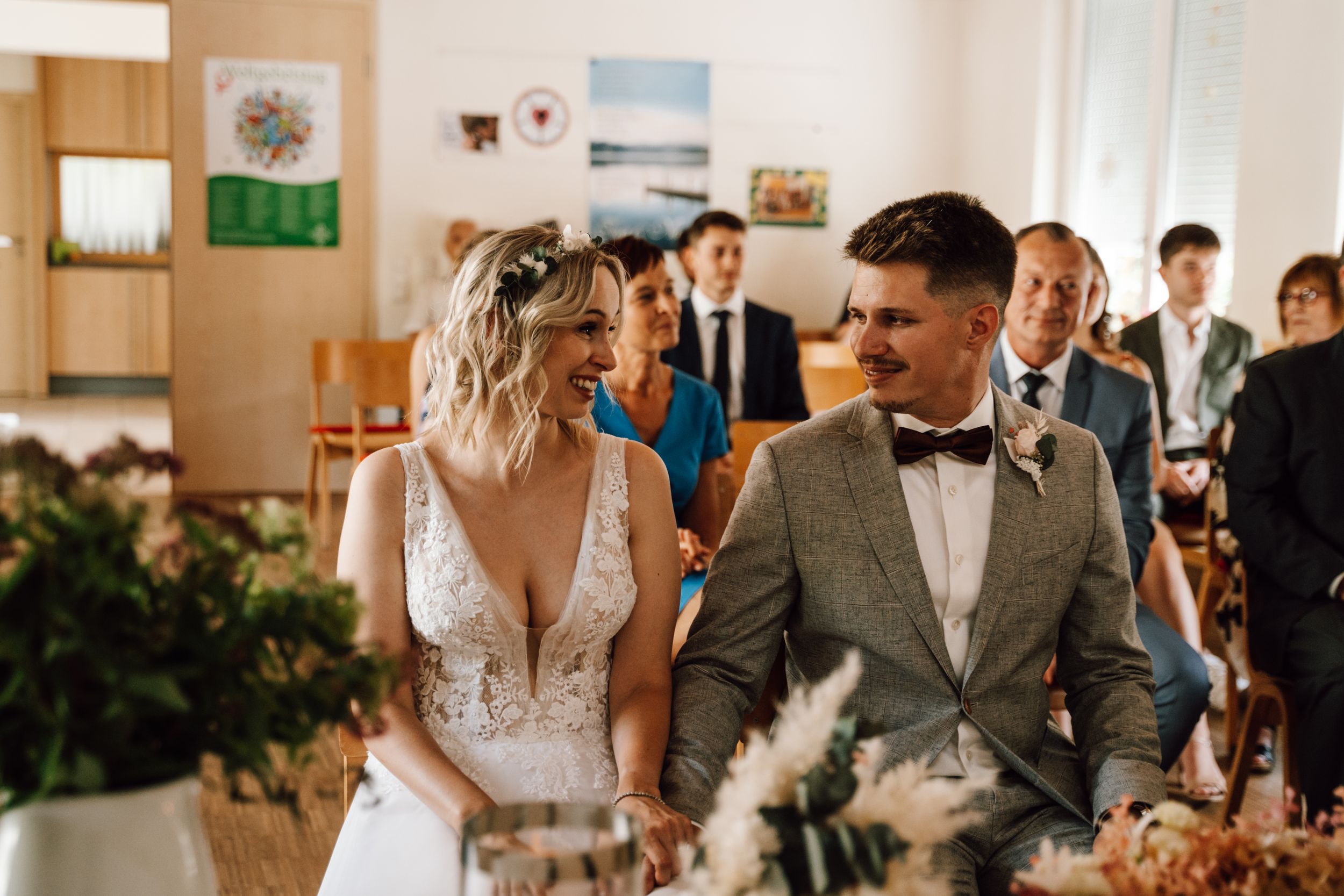 Wedding celebration in modern white room with guests watching ceremony.