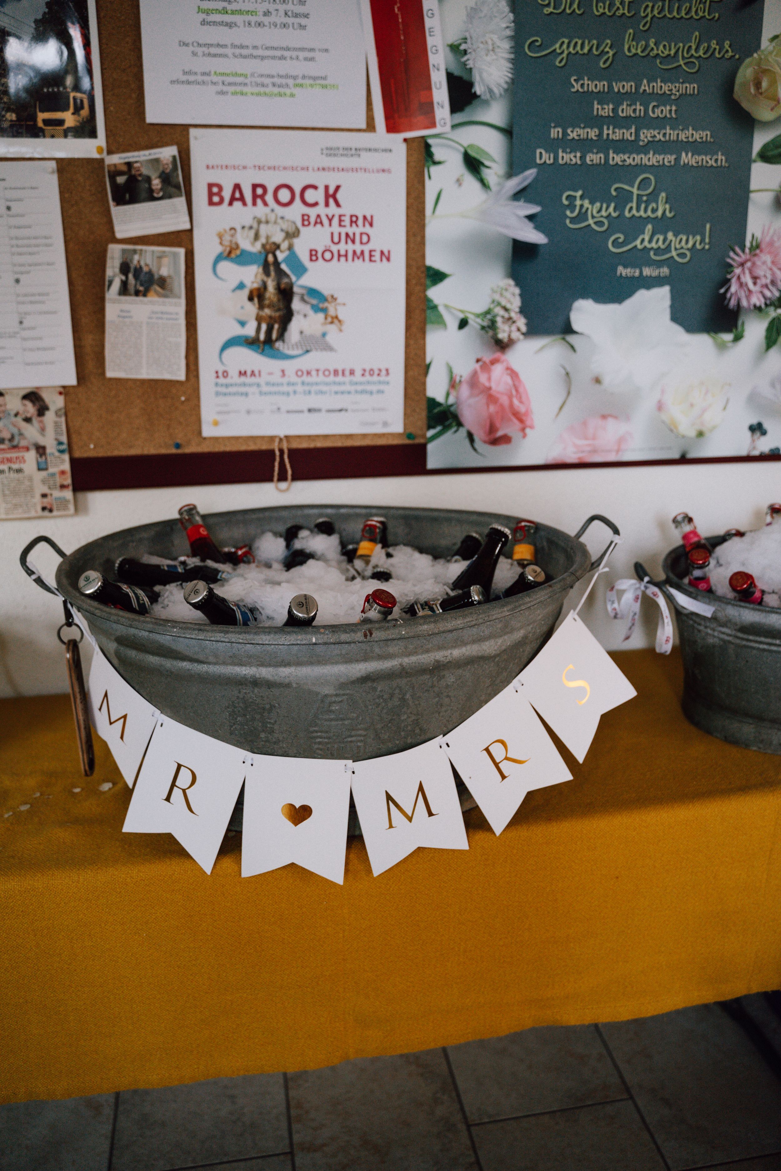 Metal tub filled with drinks and decorated with 'Mr & Mrs' banner at a wedding reception.