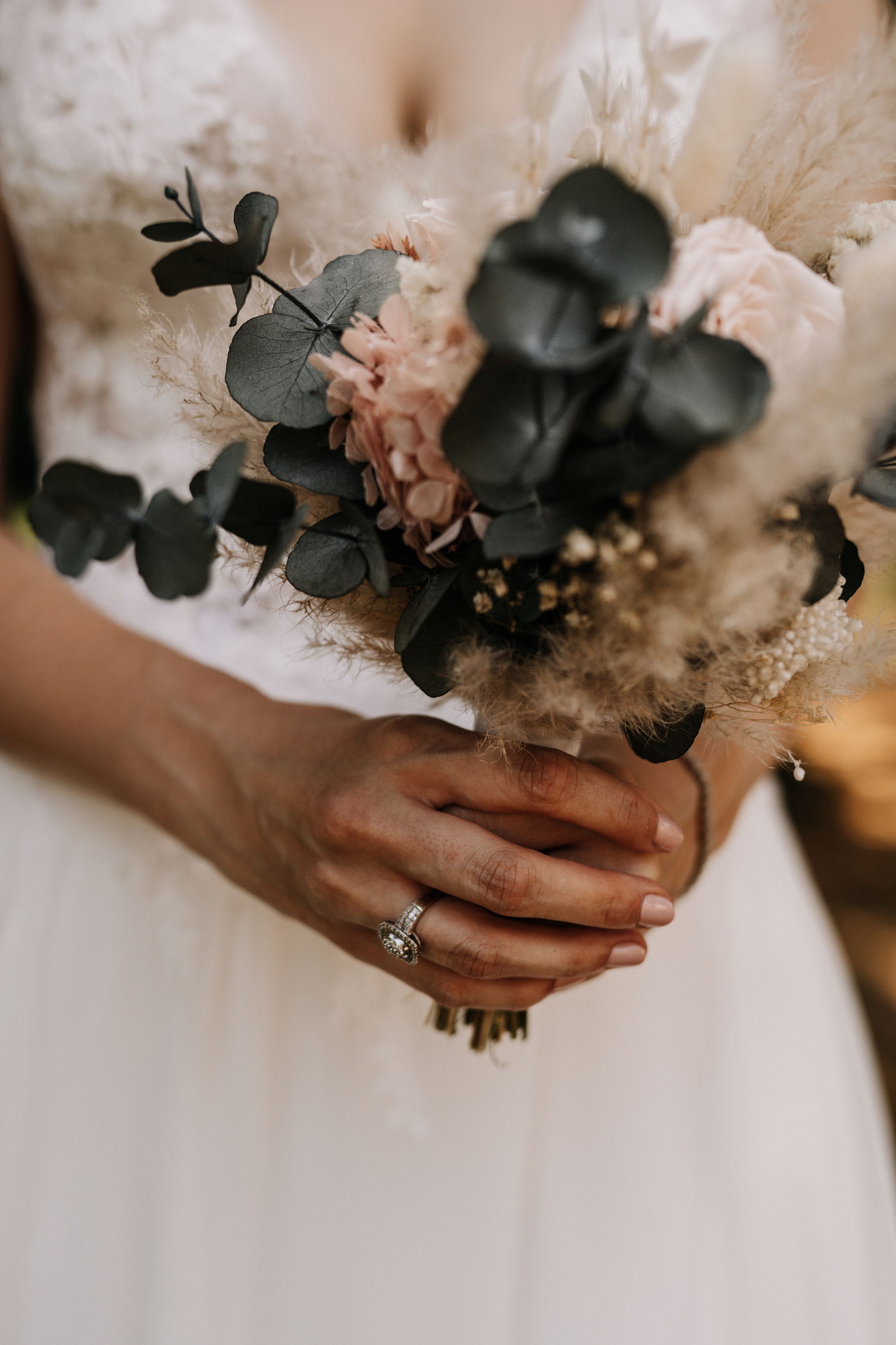 Close-up of bridal bouquet with eucalyptus leaves and blush flowers.