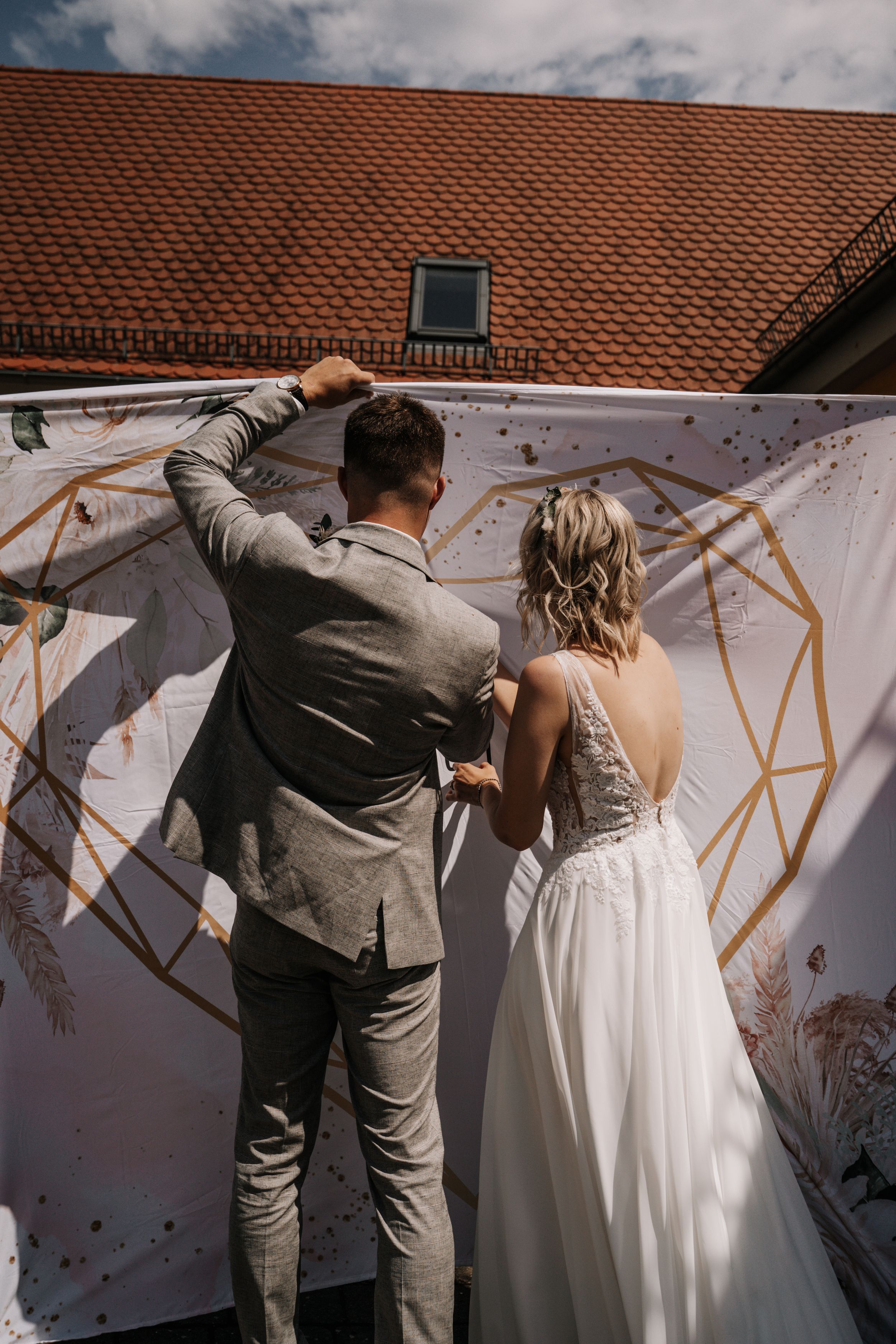 Couple working together on decorative backdrop at outdoor wedding venue.