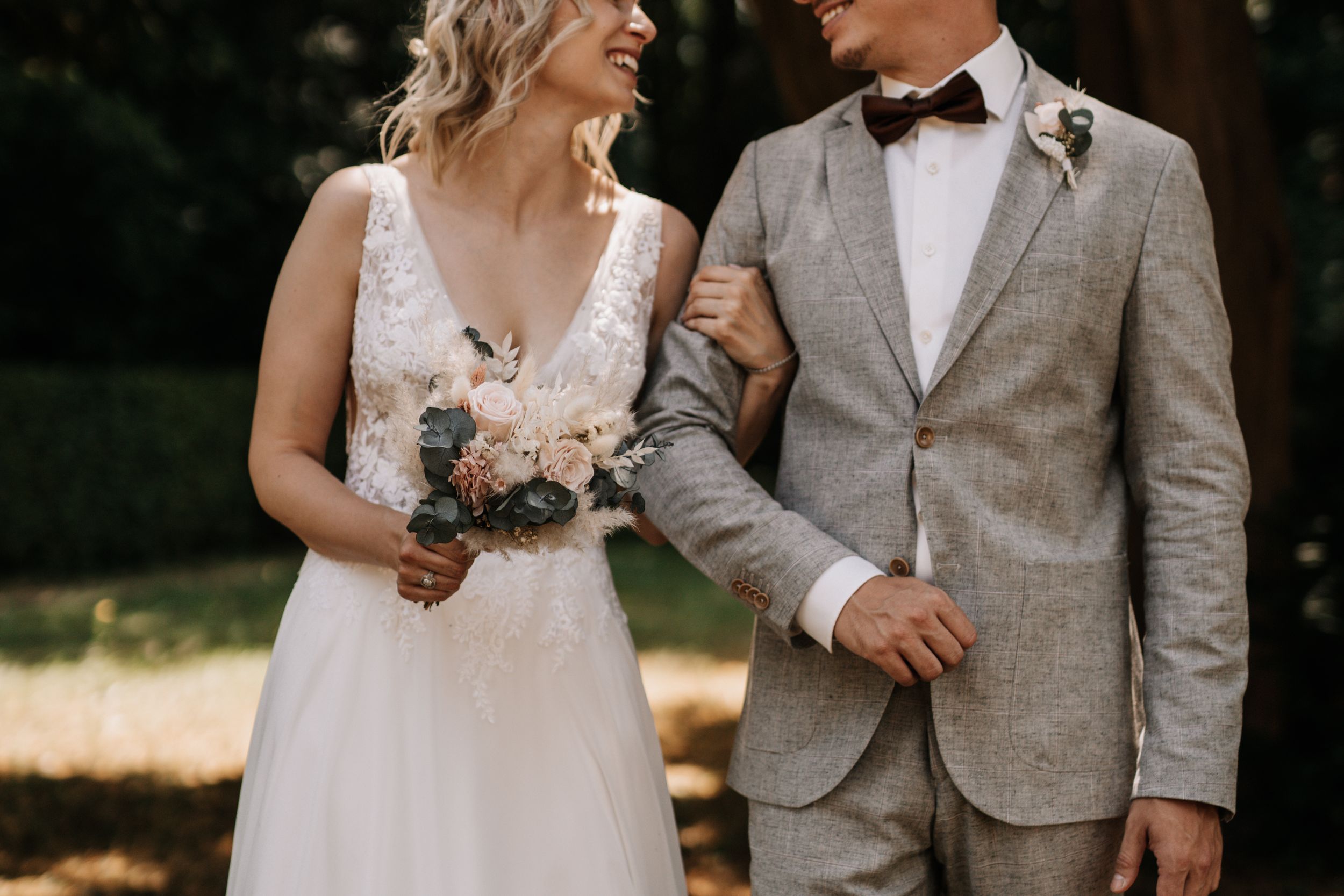 Newlyweds share a joyful moment together outdoors, with the bride holding a pink bouquet.
