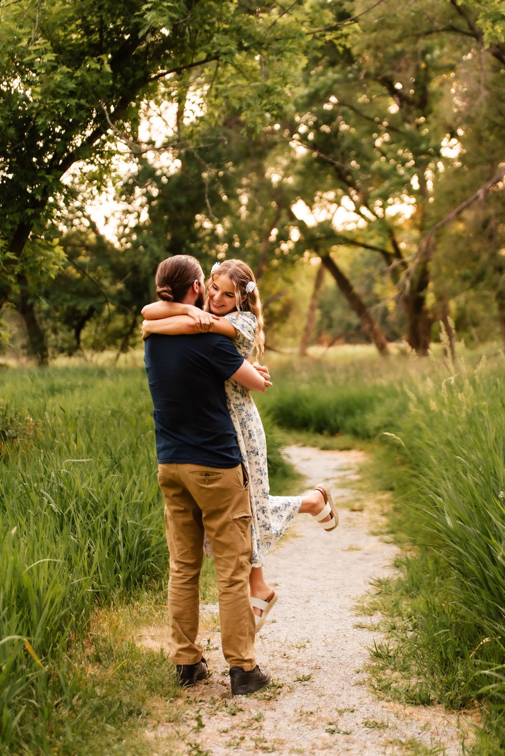 A loving embrace on a rustic path surrounded by tall grass and trees.