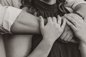 Black and white close up photograph of hands embracing and resting on a woman's chest.