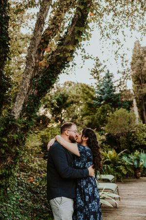 A romantic moment captured between a couple embracing in a lush garden setting on an autumn day.
