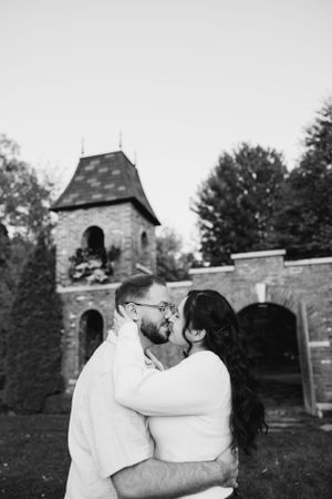 A romantic couple embraces in front of a stone church tower during an outdoor photo session.