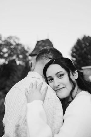 A couple shares an intimate embrace in black and white with a tower in the background.
