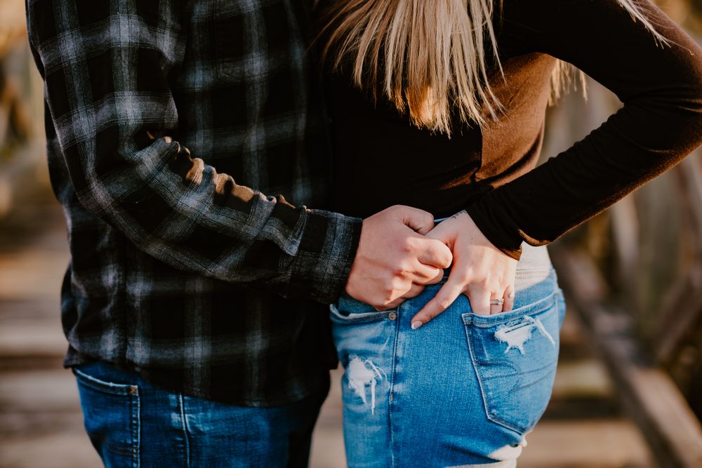 Close-up of couple holding hands while wearing casual attire of flannel and denim.
