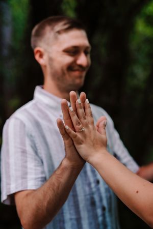 Two people give each other a celebratory high five outdoors with smiling faces and casual attire.