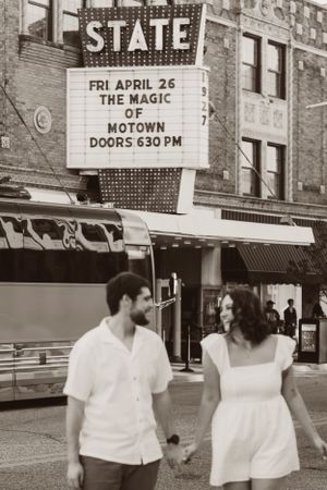 A couple walks past a vintage State Theater marquee advertising The Magic of Motown show in black and white photography.