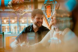 Person enjoying conversation at a pub or restaurant with blurred warm lighting and decorative elements in background.