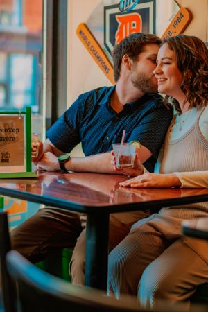 Couple sharing an intimate moment while sitting at a retro-styled diner booth with vintage decor and a cold drink.