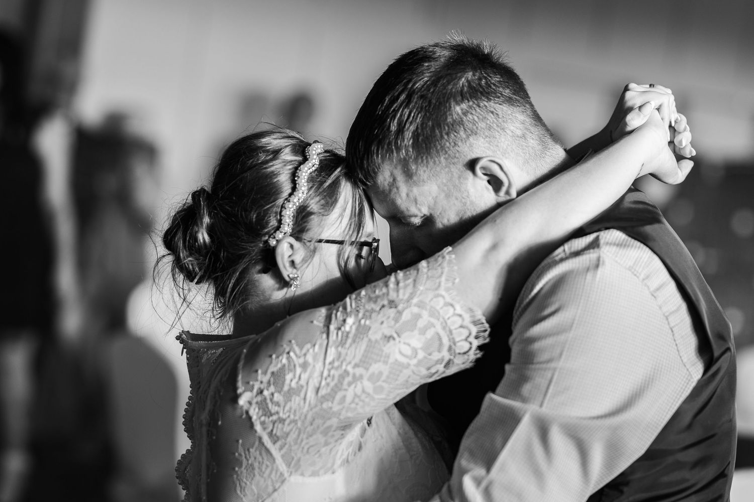 A couple shares an intimate moment under a white gazebo pillar while wearing formal attire.
