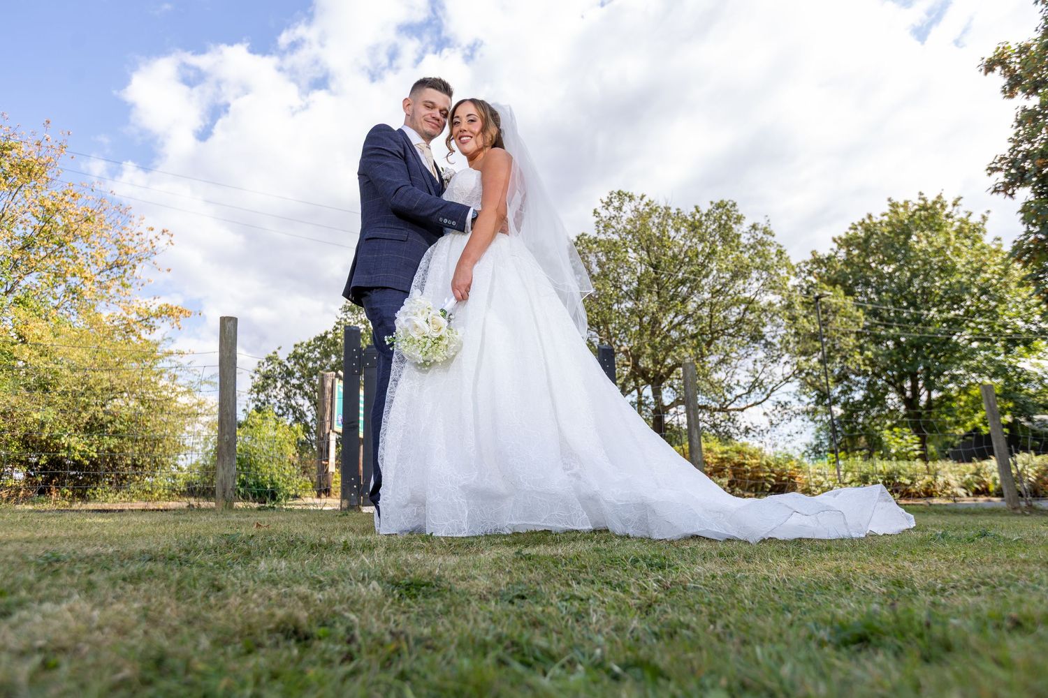A couple shares an intimate moment under a white gazebo pillar while wearing formal attire.