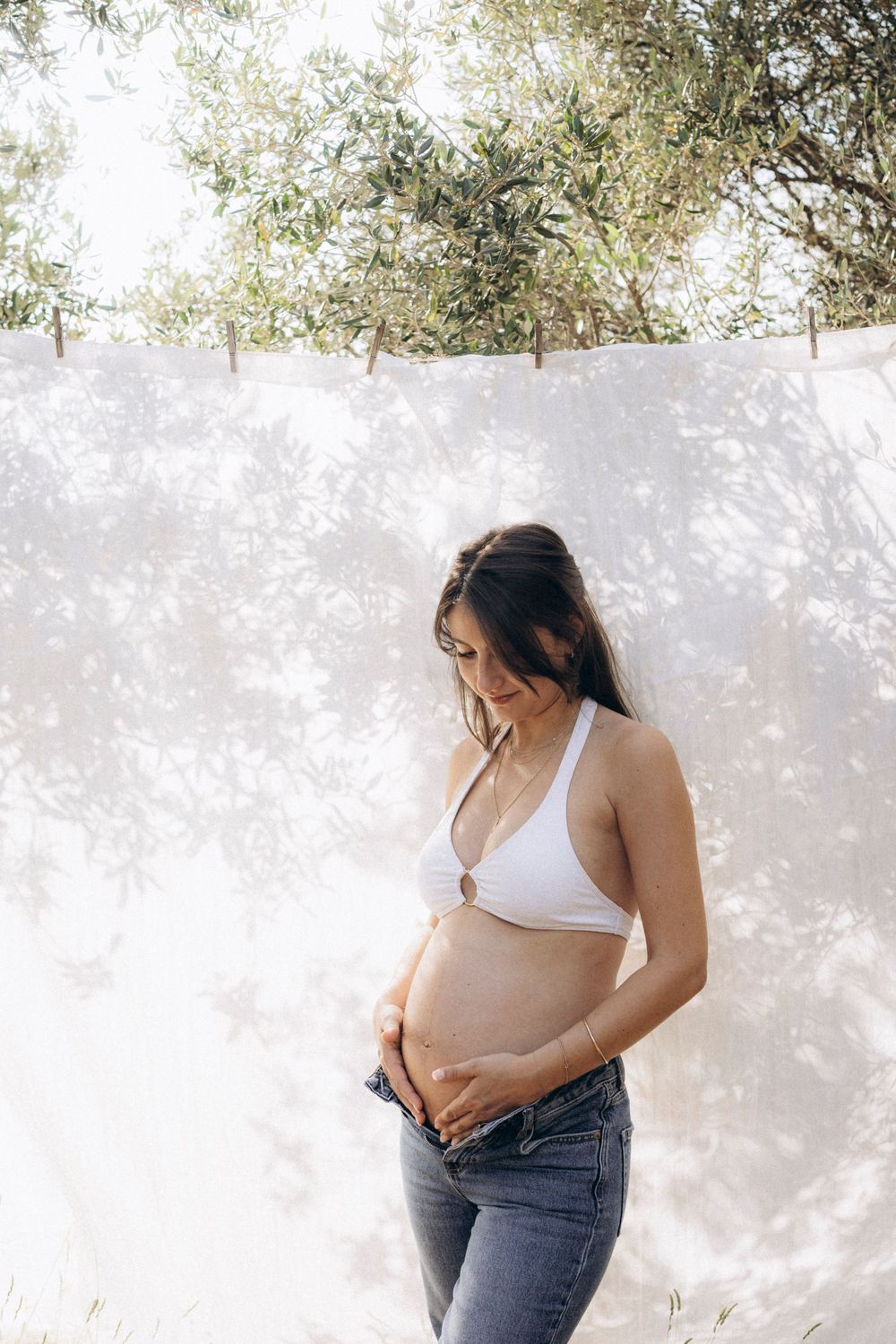 A series of fashion photos showing a woman in a beige crop top and jeans posing against a white wall outdoors.
