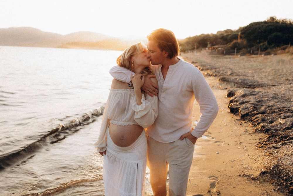 A romantic couple embraces on a beach at sunset, creating a silhouette against the golden sky and ocean waves.