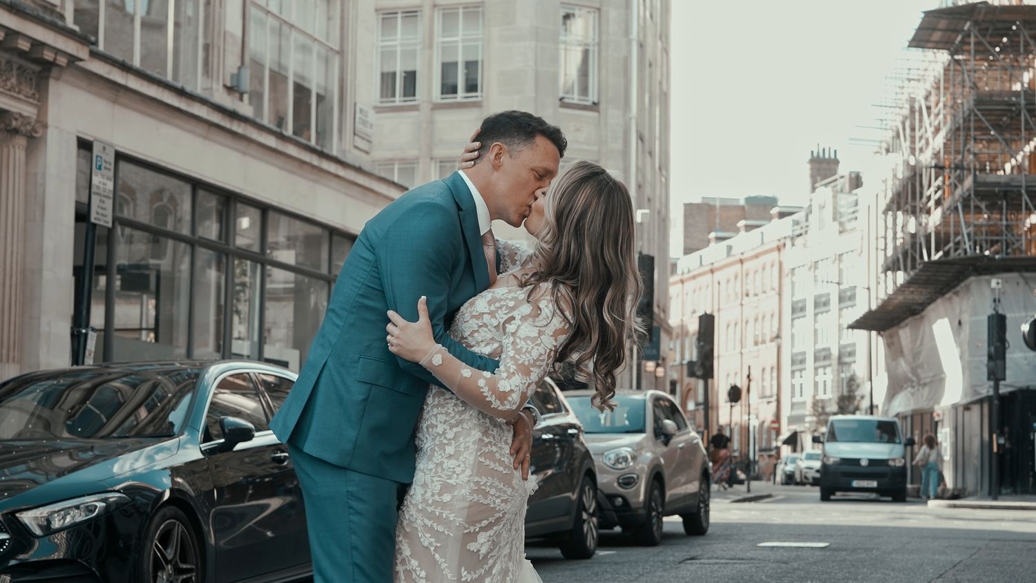 A romantic moment between a couple in formal attire sharing a kiss on a london city street.