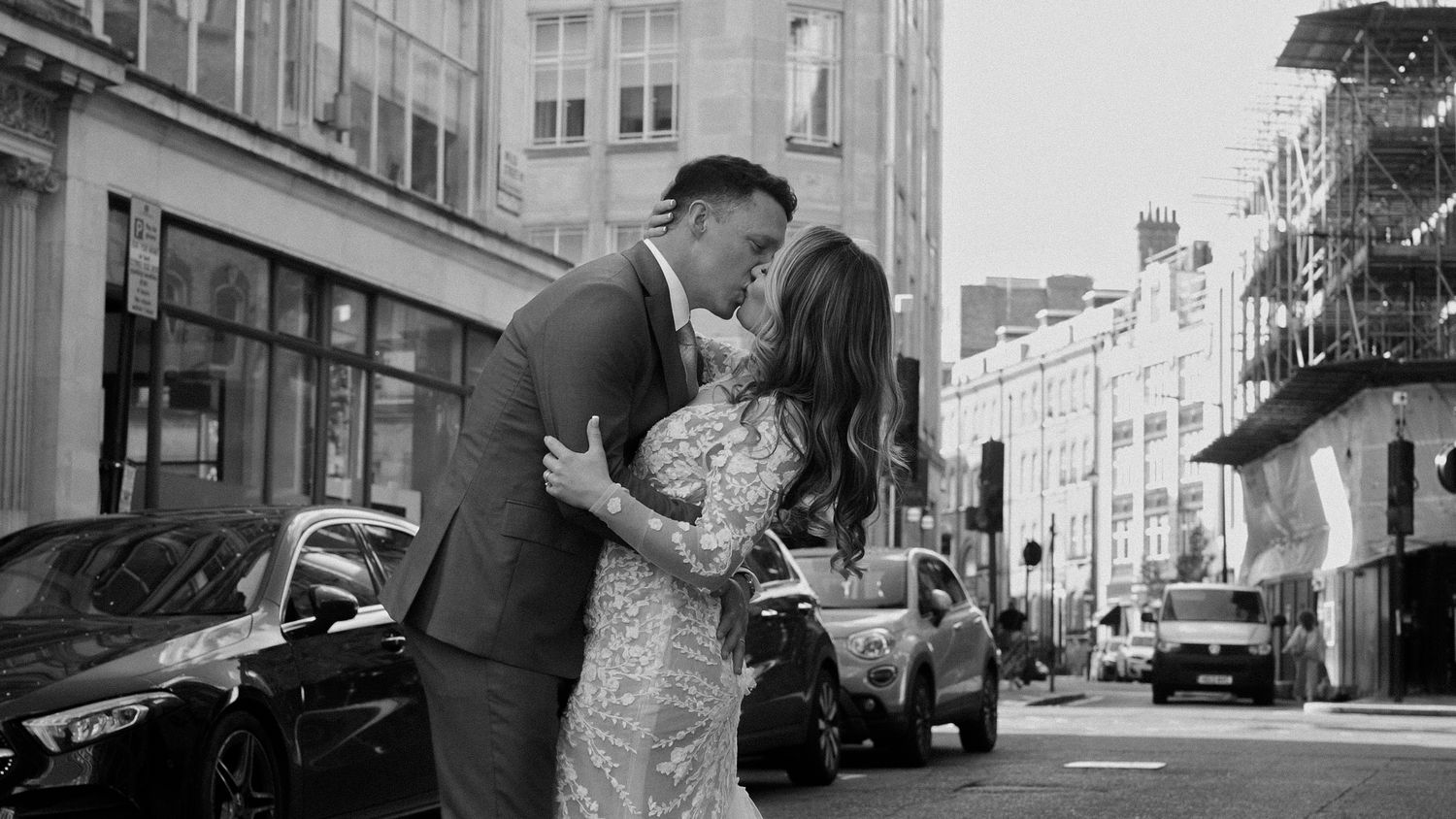 A romantic moment between a couple in formal attire sharing a kiss on a london city street.